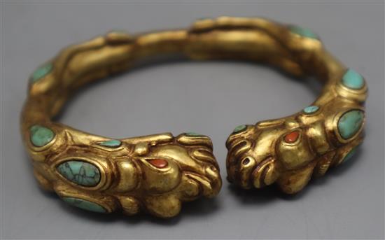 A Tibetan gilt metal and turquoise set open bangle.